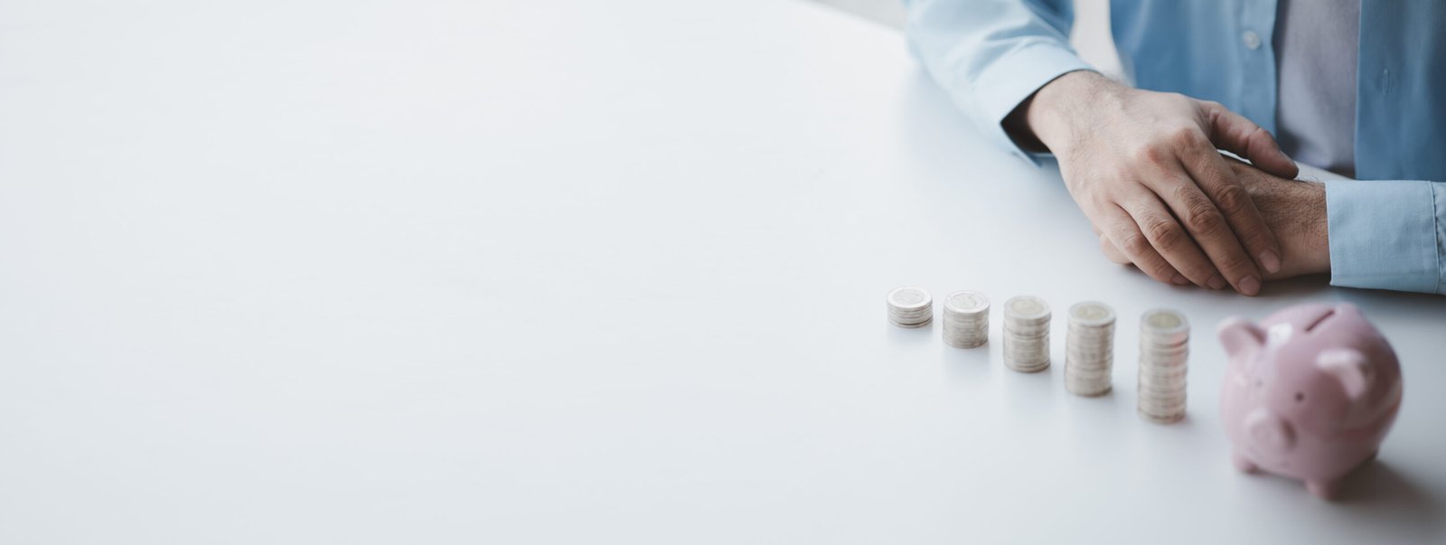 Person with pile of coins and piggy bank